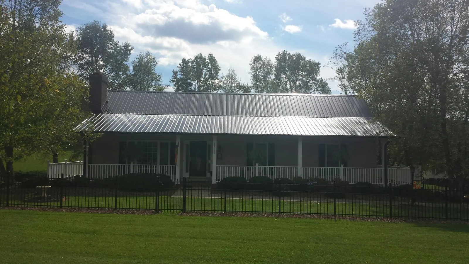 Gray metal roof on a brick ranch with a full width front porch — Gutter Guard Installation work by our crew in Pfafftown